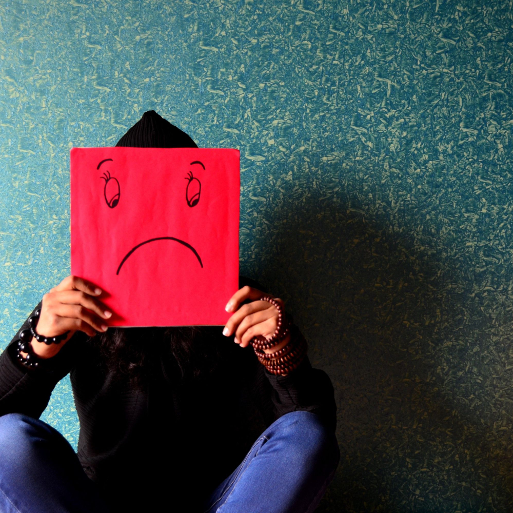 person holding a picture of a sad face