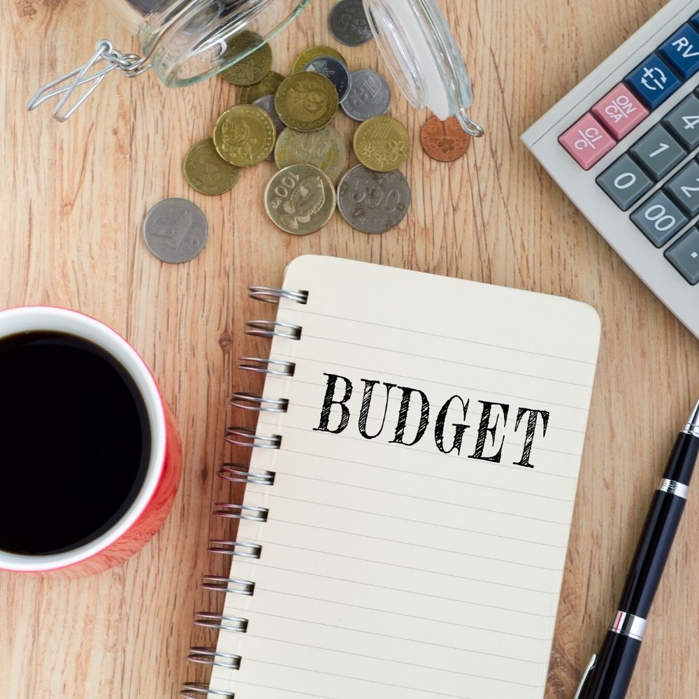 notebook with budget written on the front money coffee and pen