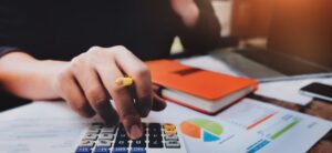 person with pen in hand and a calculator