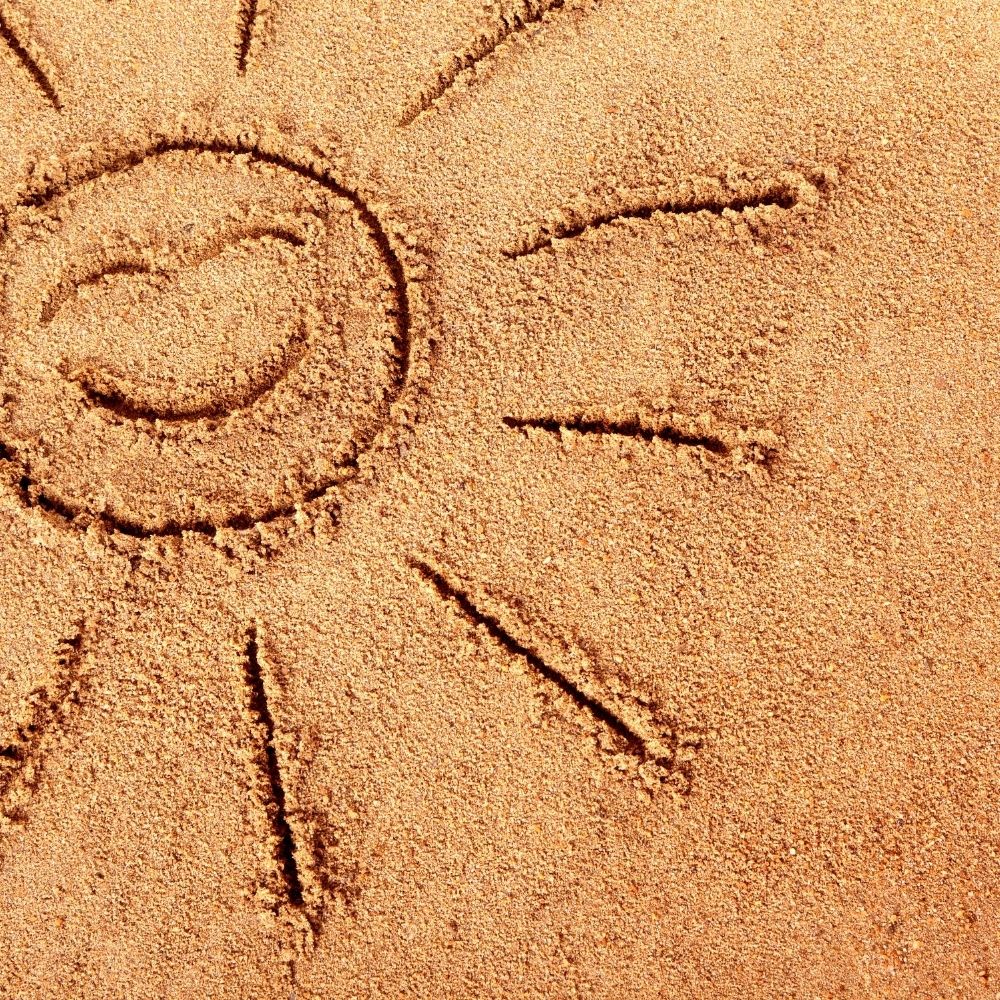 sun drawn in the sand with a happy face