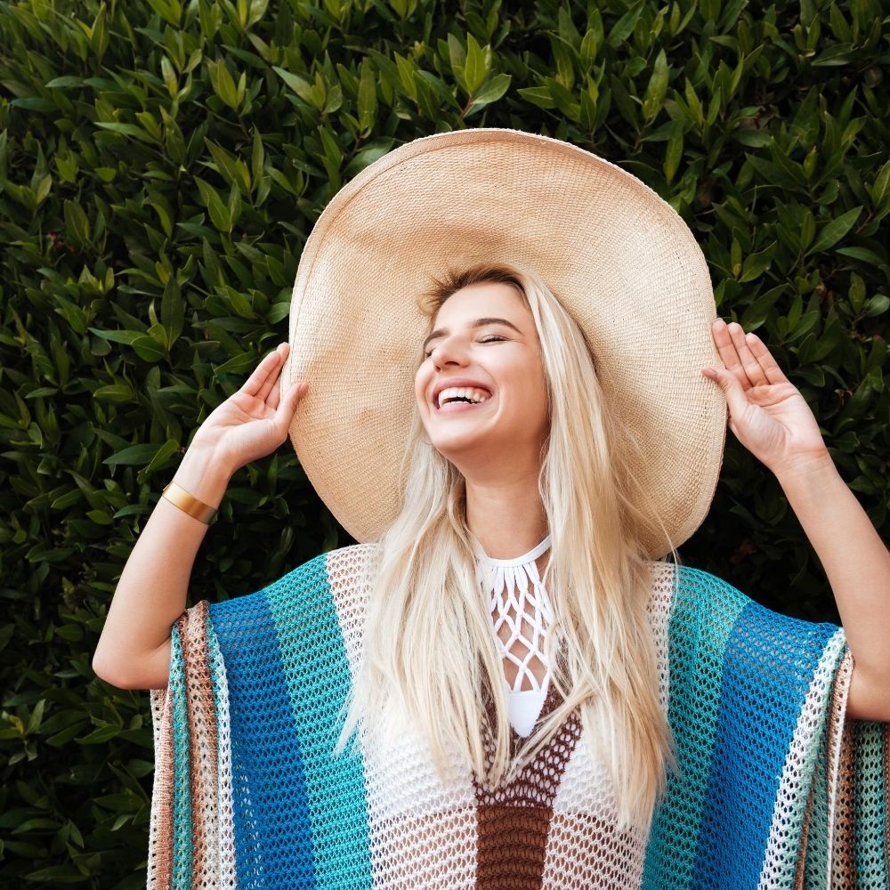 women in large hat smiling