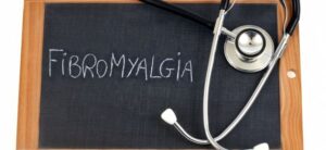 Fibromyalgia written on a chalk board with a stethoscope by it
