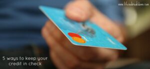 A hand holding a blue credit card with orange and red circles. The text reads, 5 ways to keep your credit in check.