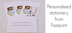 Three business cards with an illustration of a woman under a rainbow and a dog beside her. Text reads Life in a Breakdown. Contact details on the bottom card. On the right, text says Personalised stationery from Fastprint.