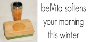 A bamboo travel mug and a container with a biscuit on a wooden lid are displayed. Text reads: belVita softens your morning this winter.