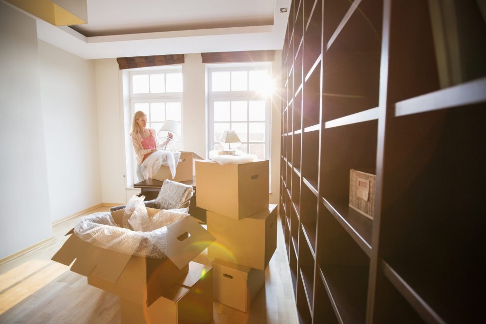 Woman unpacking lamp from moving box at new house