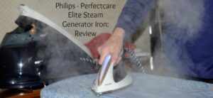 A person ironing a blue patterned fabric with a Philips Perfectcare Elite Steam Generator Iron. Steam is visibly emitting from the iron. Displayed text reads: Philips - Perfectcare Elite Steam Generator Iron: Review.