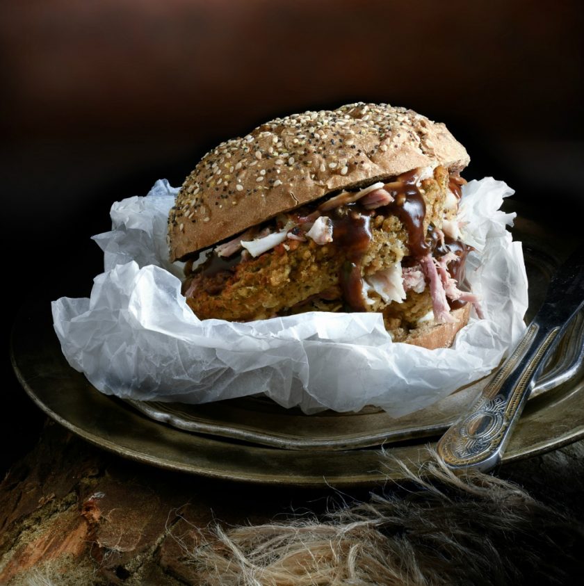Pork, sage & onion stuffing and rich gravy, the Ultimate Pulled Pork Roll. The perfect image for your restaurant or bistro menu designs. Shot in creative lighting in a rustic setting against a dark background. Copy space.