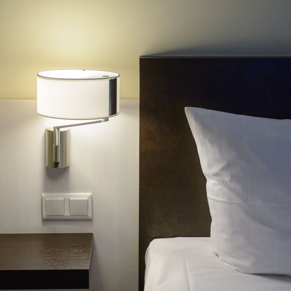 lamp mounted on wall by bed