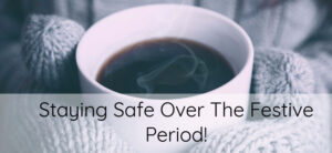 A person in gray knitted gloves holds a steaming white mug filled with a dark liquid. Over the image is text saying, Staying Safe Over The Festive Period!.