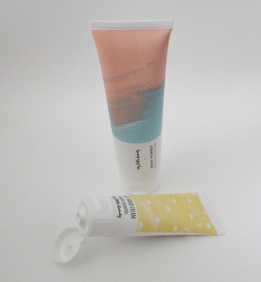 My Little Box January 2017 Body Lotion in a tube light pink to the top, blue to the bottom standing up in photo. Hand cream is laying down below and is in a yellow tube.