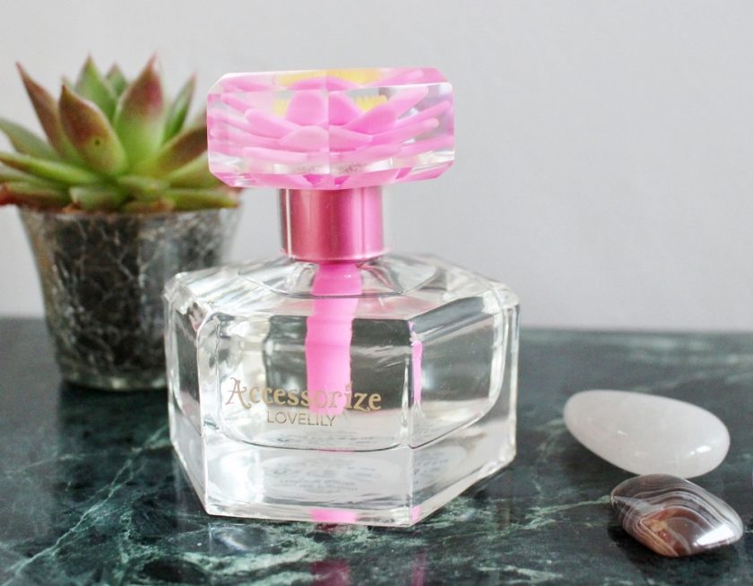 accessorize lovelily view from the front of the perfume it is hexagonal in shape and clean, the neck has a metallic pink surround, while cap includes a pink material flower,