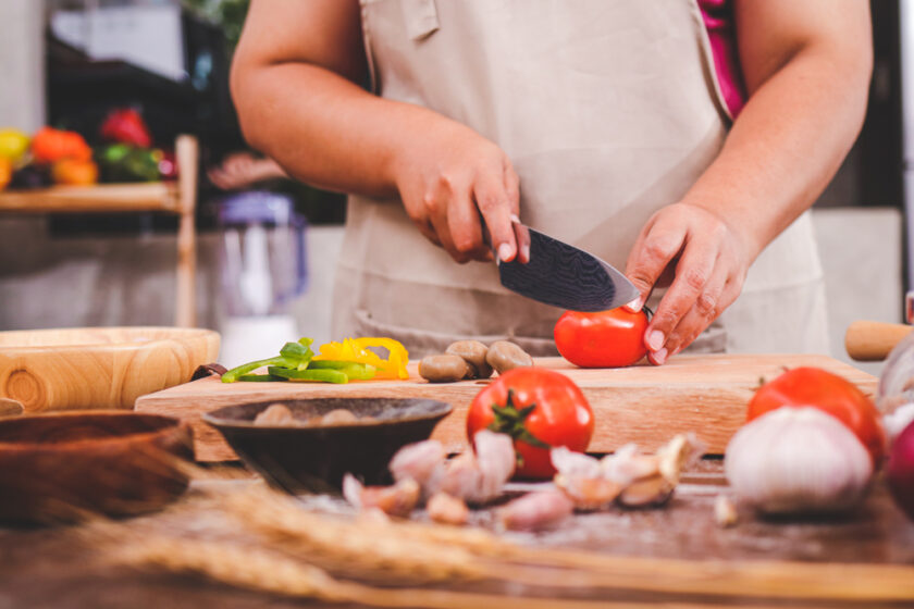 Woman cooking in the kitchen slicing tomatoes.