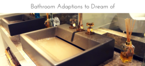 Modern bathroom sink with sleek brown basin, gold faucets, and marble countertop. A reed diffuser and glass decor sit beside the sink. Above, text reads: Bathroom Adaptations to Dream of.