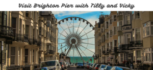 Street view leading to Brighton Pier with a Ferris wheel in the background. The sea is visible at the end of the street, flanked by buildings on both sides. Text at the top reads, Visit Brighton Pier with Tilly and Vicky.