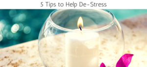 A lit white candle is inside a glass holder on a textured surface. Pink petals are nearby, and there is a blue-green blurred background. The text above reads, 5 Tips to Help De-Stress.