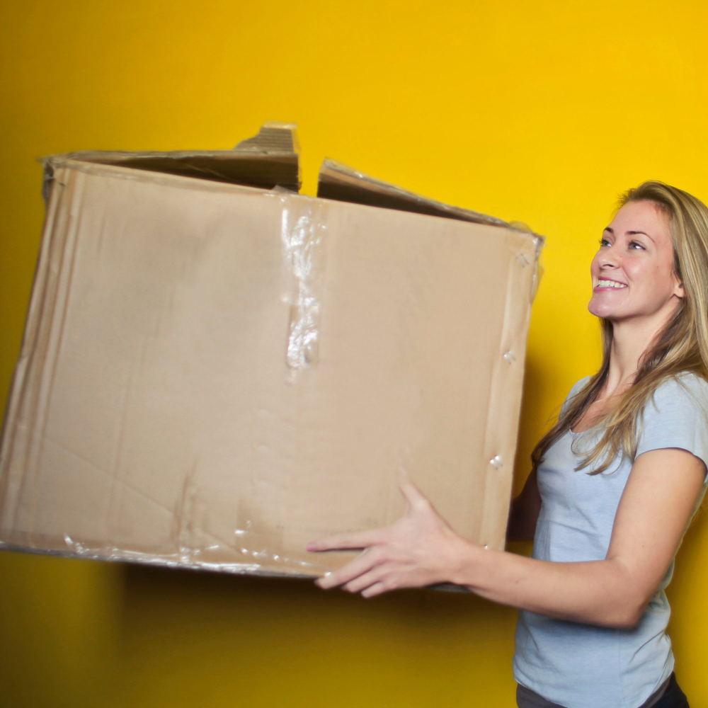 women holding a large box with yellow background