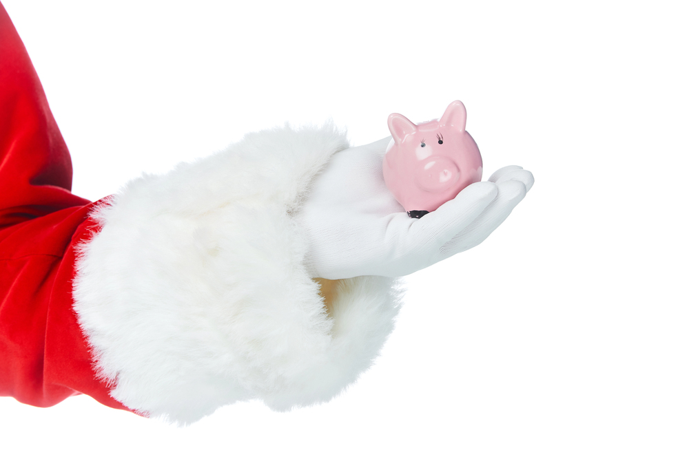 Father Christmas in a white glove holds a small pink piggy bank, encouraging you to start saving for Christmas.