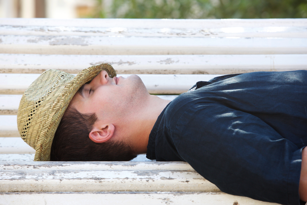 Side portrait of a man sleeping on park bench outside