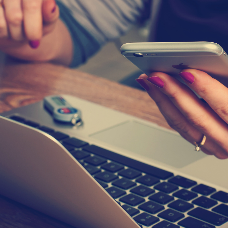 Lady sat at a computer with phone in hands