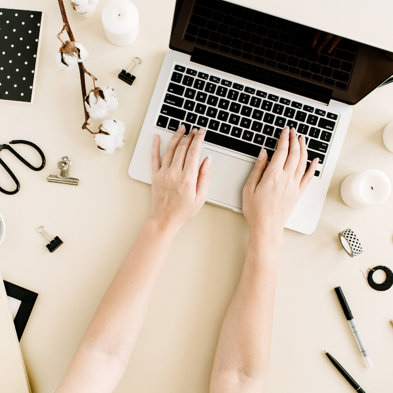 person typing on laptop with accessories around them