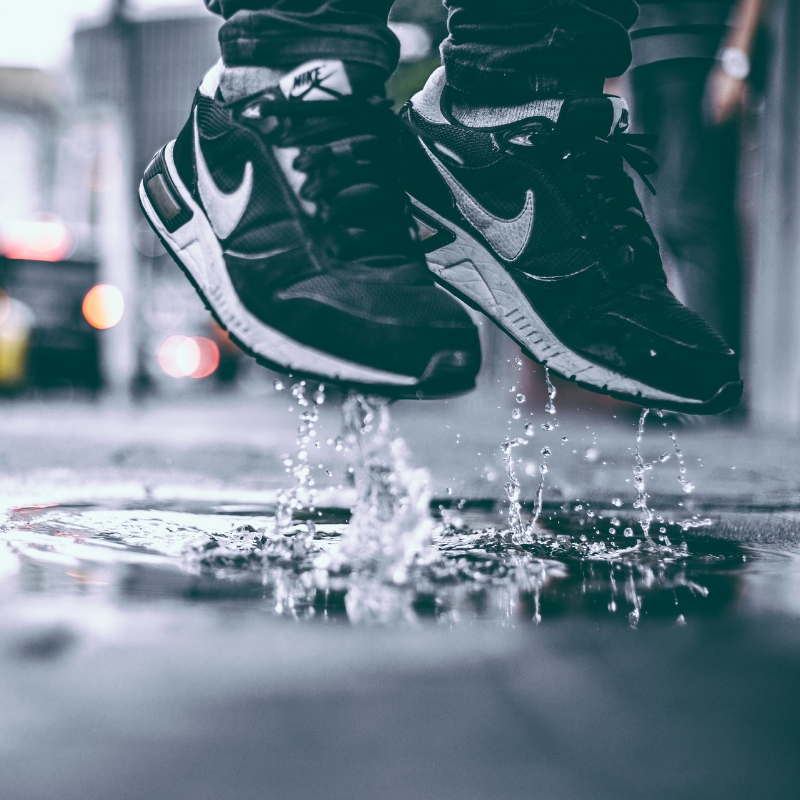 someone wearing trainers jumping in a puddle