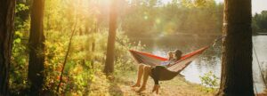 Two people sat on a hammock by a lake