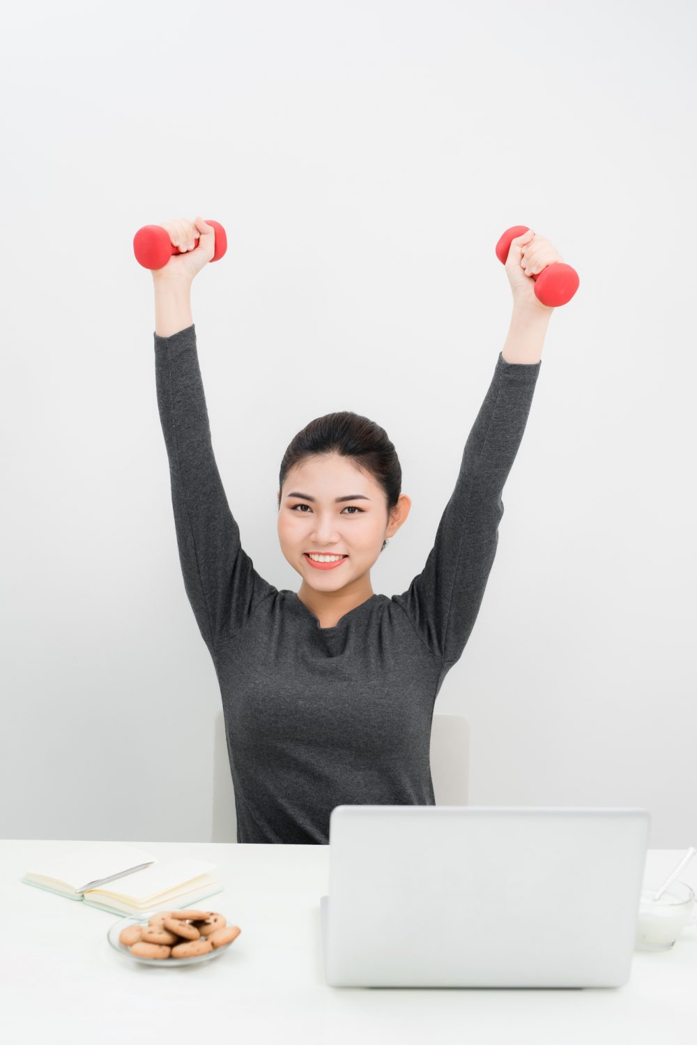 Young businesswoman doing exercise with fitness dumbbells in office