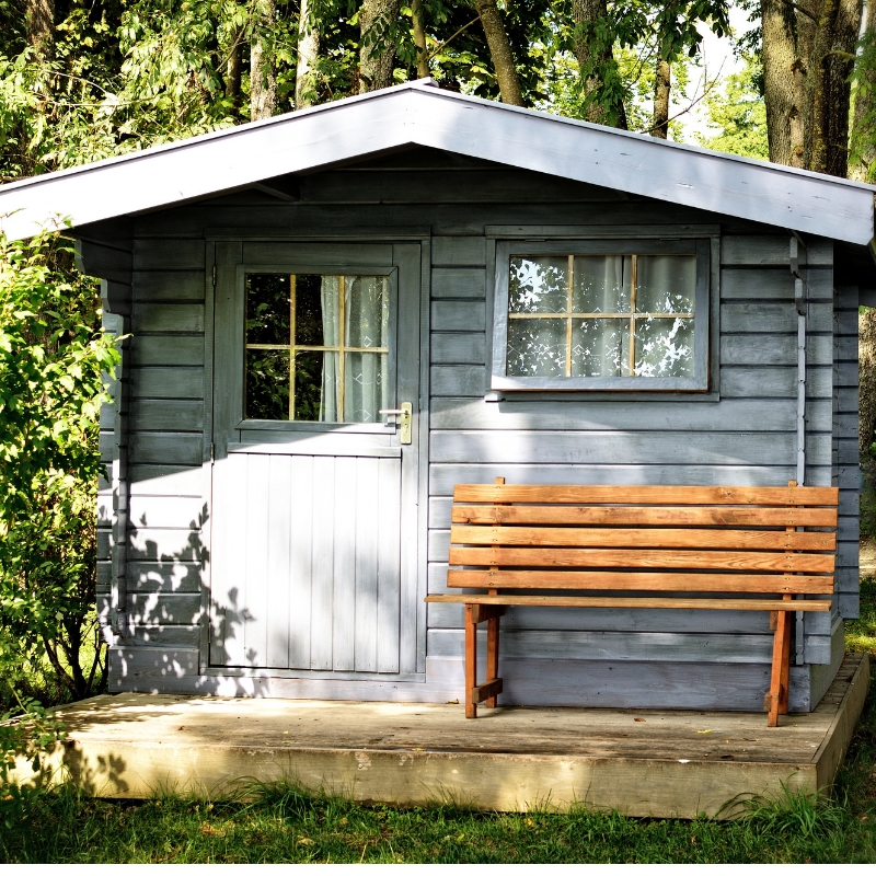 blue garden shed with a bench outside