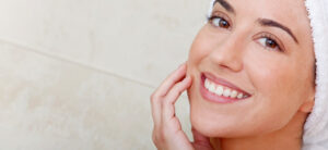 lady looking at the camera, touching her face and with a towel on her face