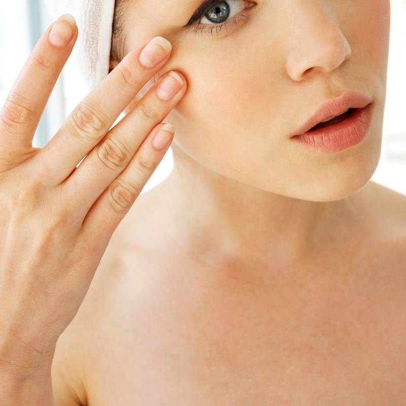 lady with her hand on her face as if applying cream or serum