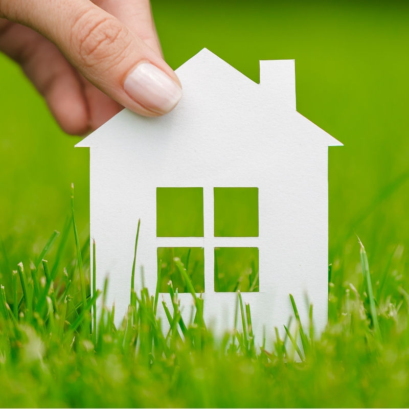 person holding the shape of a house in grass