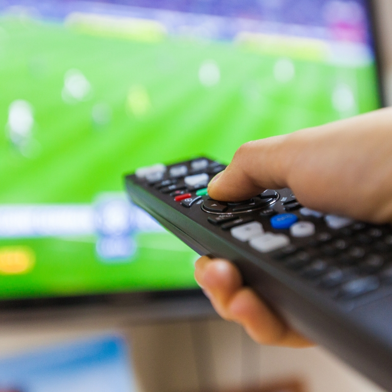picture of a tv in the background and a controller in someones hand