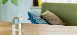 cup of water with a green sofa and cushion in the background