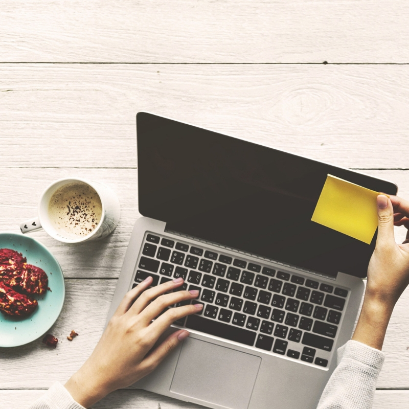 someone sat at their laptop with food and a drink