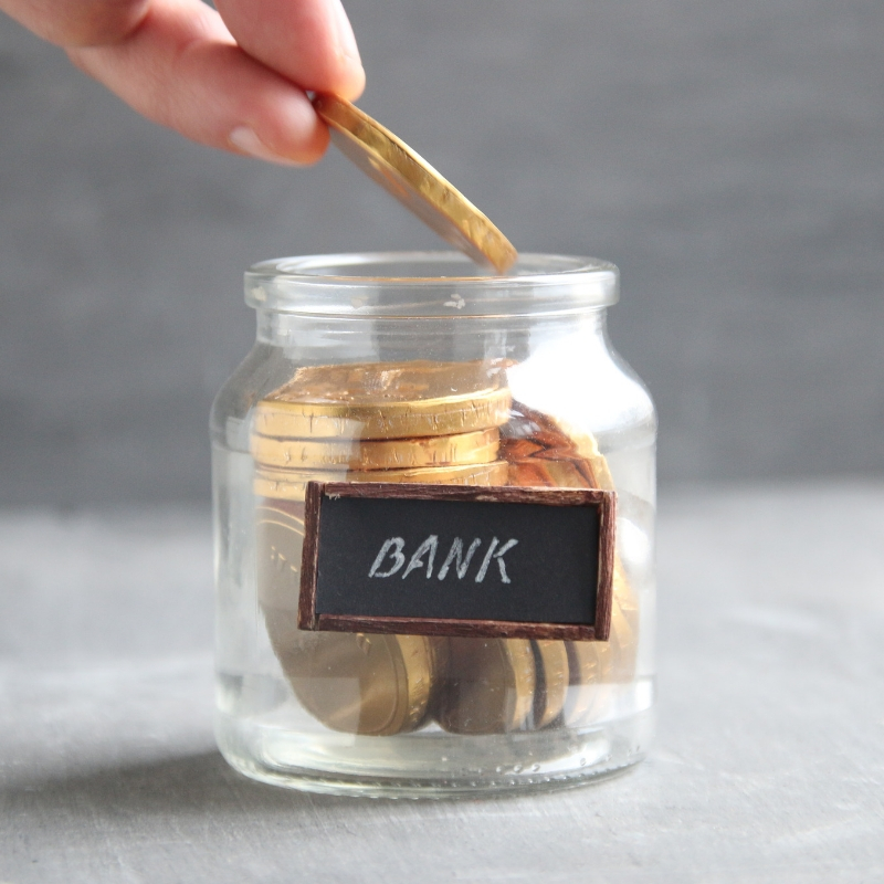 large gold coins in being put in a jar labelled bank