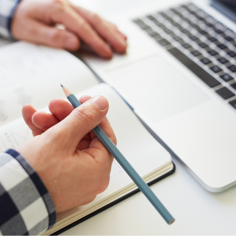 person with a notebook in front of their computer