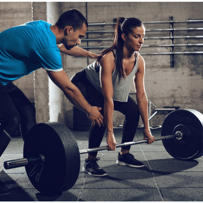 personal trainer helping a lady weight lift