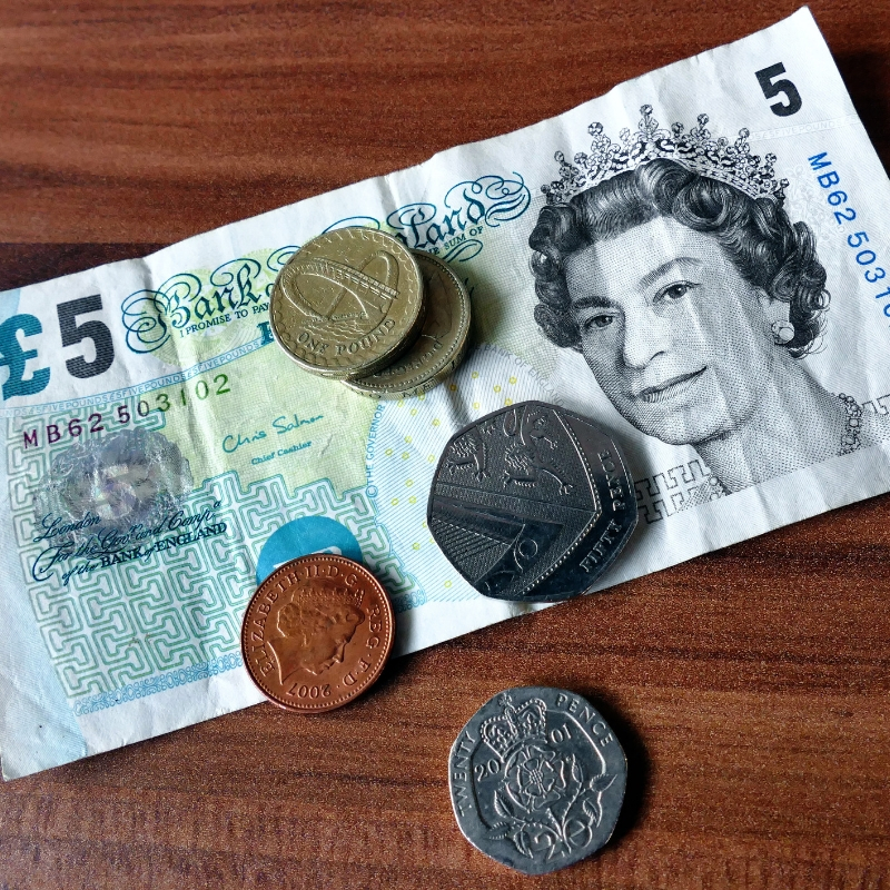 selection of coins and a five pound note