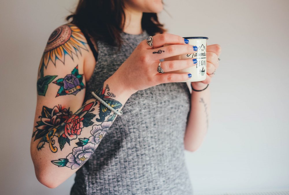 women with tattoos holding a mug