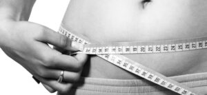 person holding a tape measure around waist