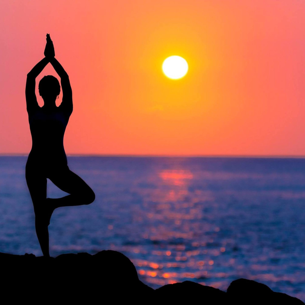 someone practising yoga at sunset