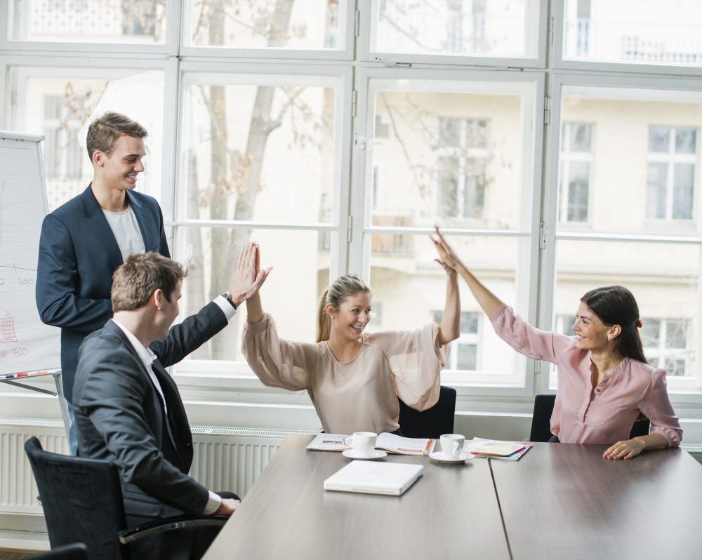 Young business team doing high five at conference table