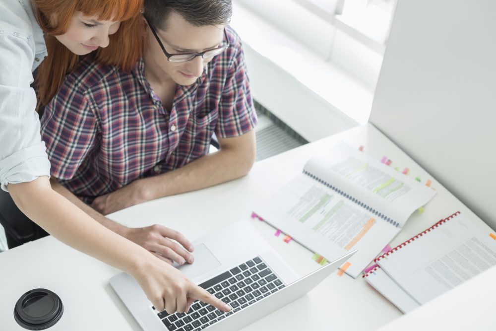 Business couple using laptop in creative office