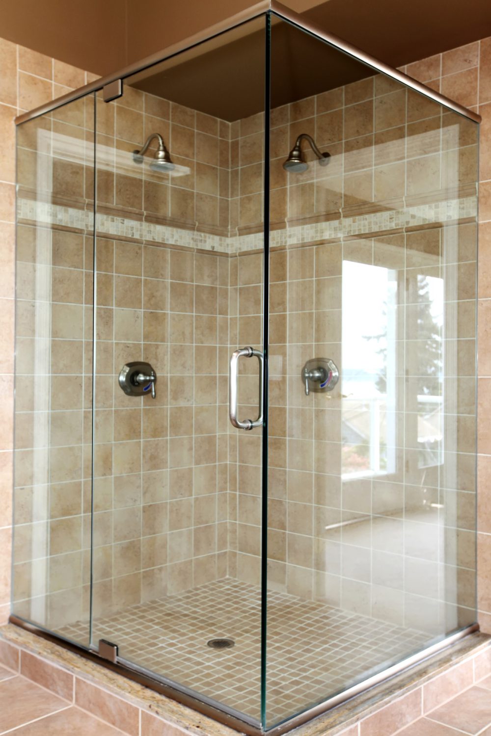 Modern new glass walk in shower with beige tiles and two heads.