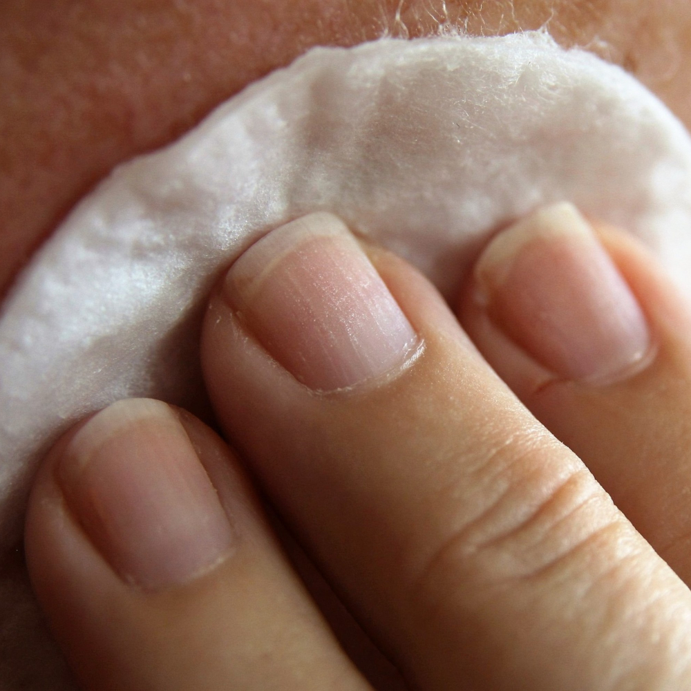 cotton wool pad being held to a face
