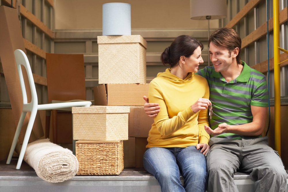 Two people sat on the back of a moving truck taking a break