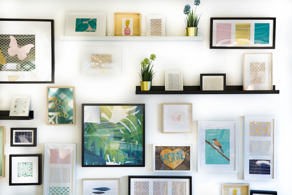 A wall decorated with picture frames, shelves and plants