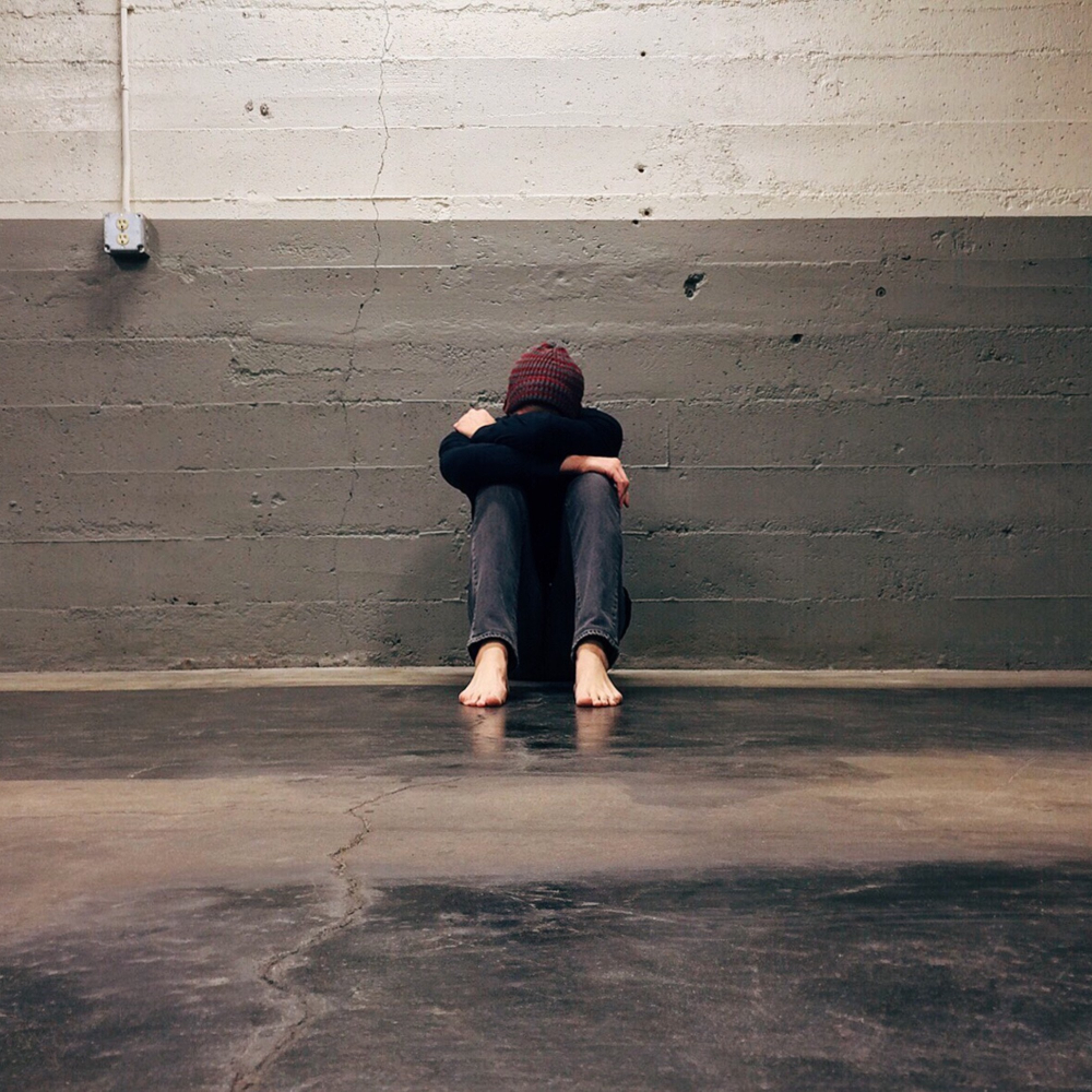 person sat against the wall with head down