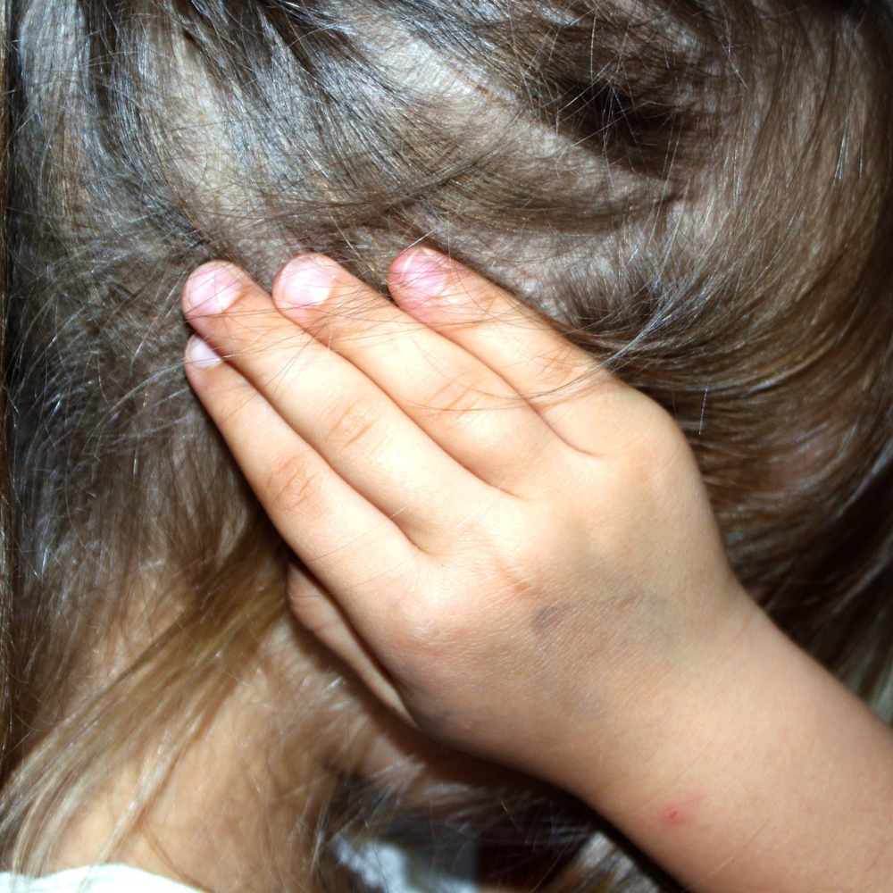 child with hands over their face